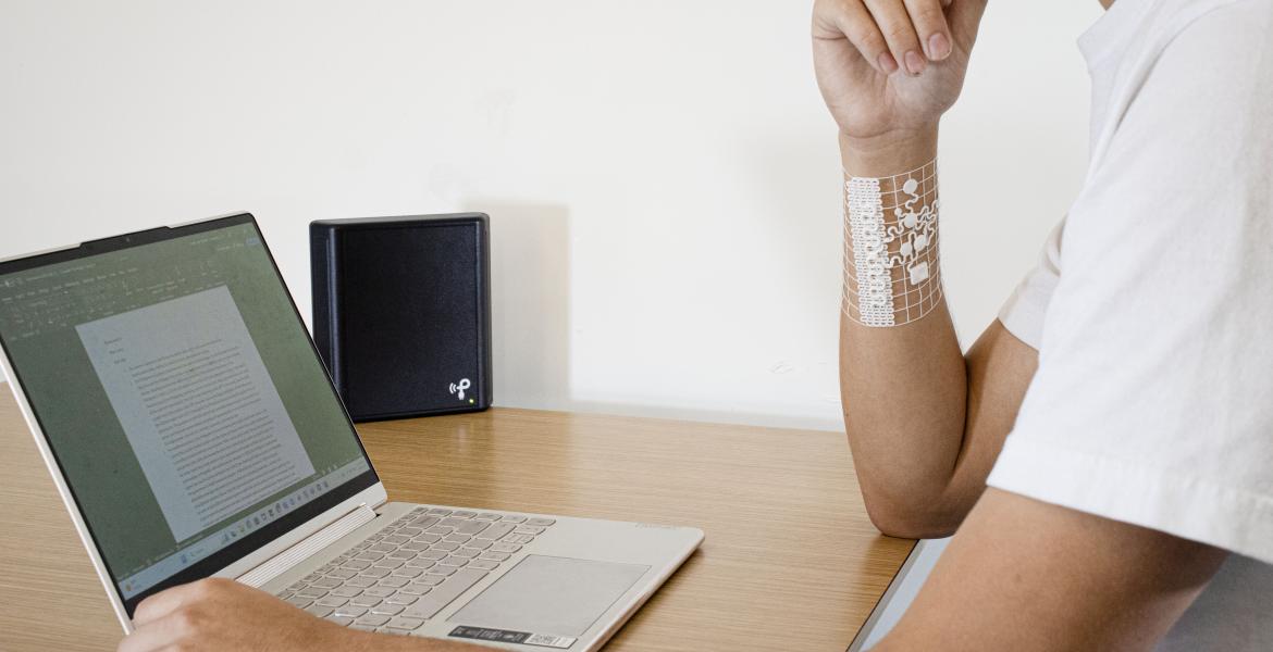 a person models the device while sitting at desk with a computer