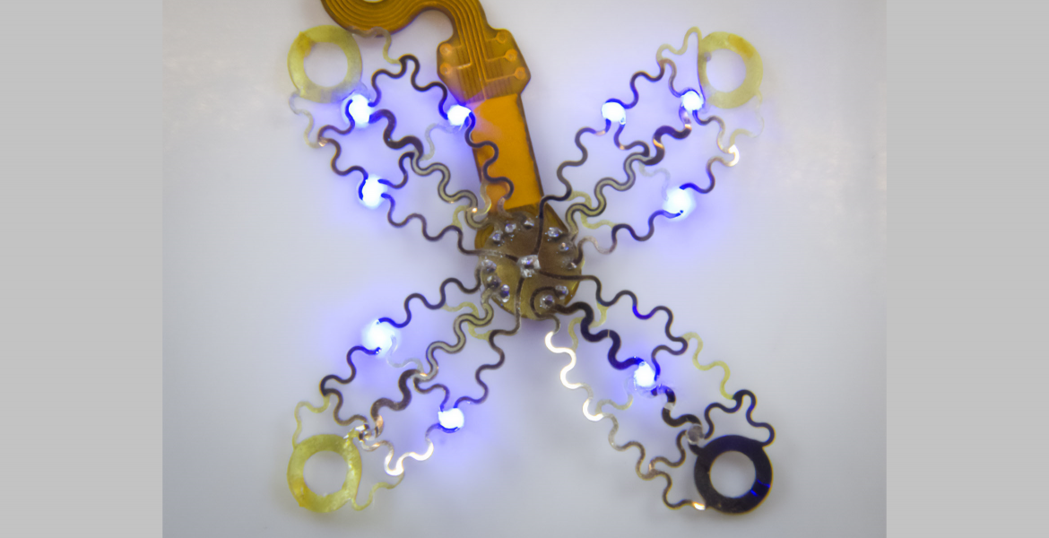 a device that looks like metallic mesh has four petal like pieces radiating from the middle. it is lit up with small blue lights.
