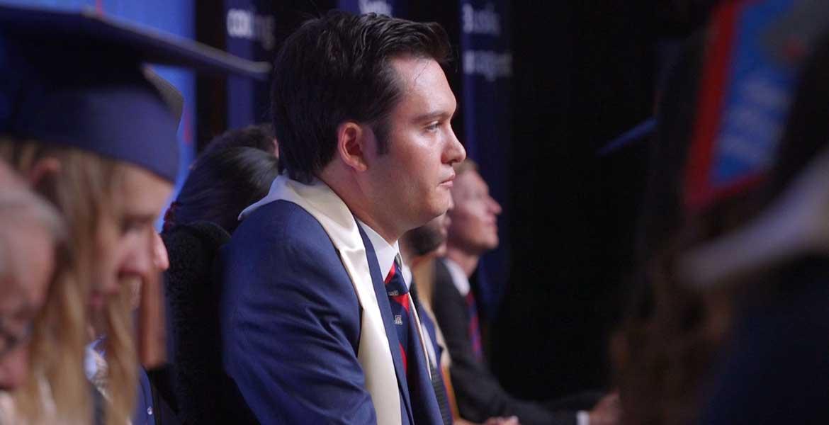 Profile photo of Jeffrey Bristol, sitting in a blue suit and graduation sash, looking straight ahead.