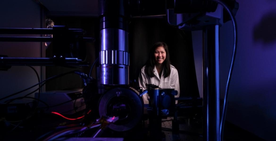 Judith Su in her lab with FLOWER. The lab is dark and lit with blue and purple lighting.