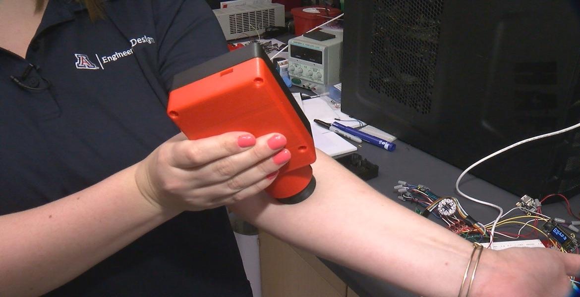 Close up of a woman holding a plastic device onto her left arm.