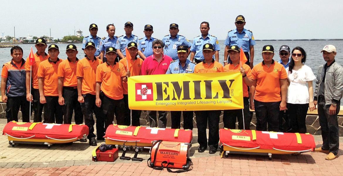 a large group of people pose near water with rescue equipment