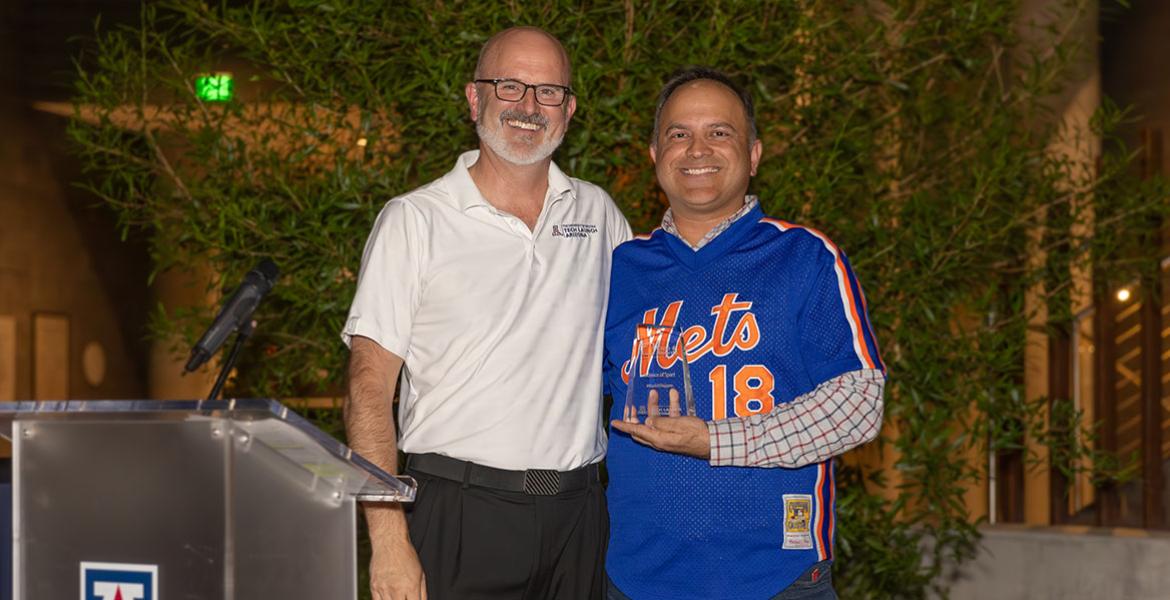 Two men stand at a podium with an award