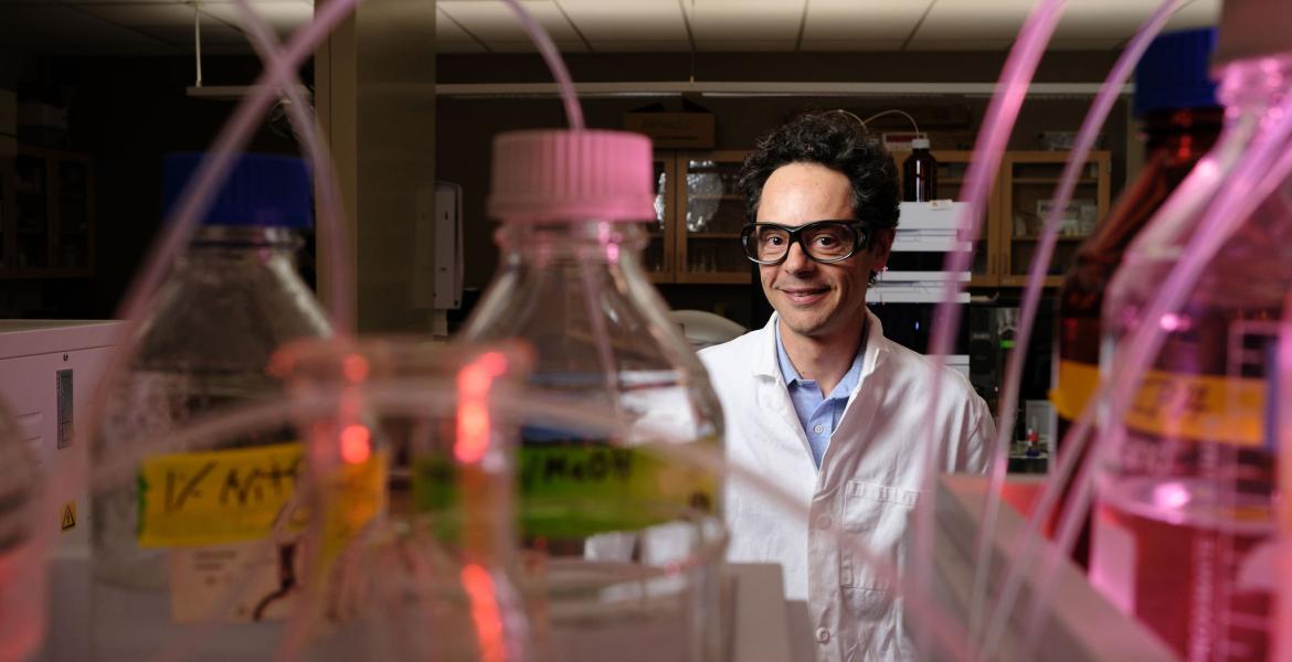Andrea Achilli in his lab, with beakers in the foreground of the photo.