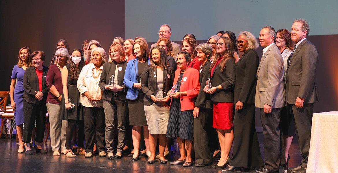 Women of Impact awardees stand on a stage