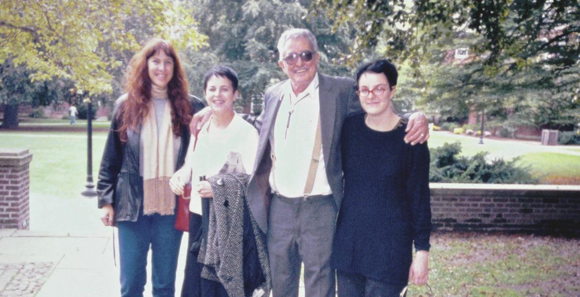 Four people (three women and one man) standing and smiling on a college campus.