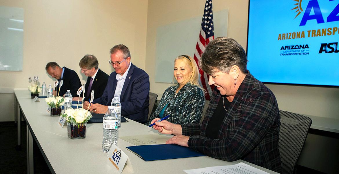 5 people sign documents at a table