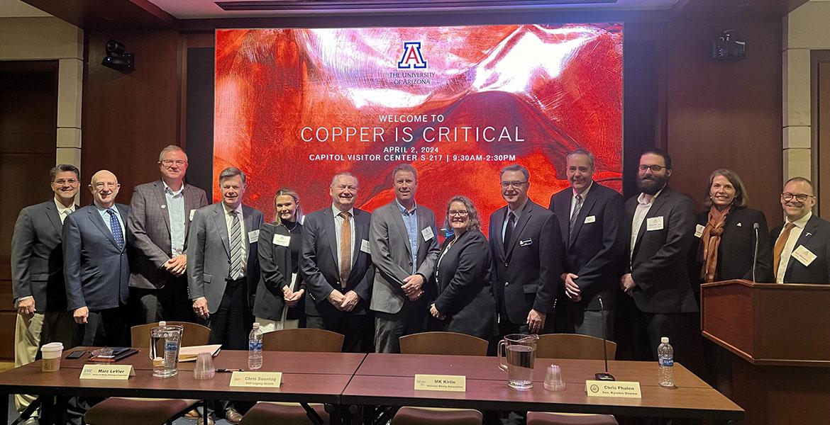 a large group of panelists poses in a conference setting