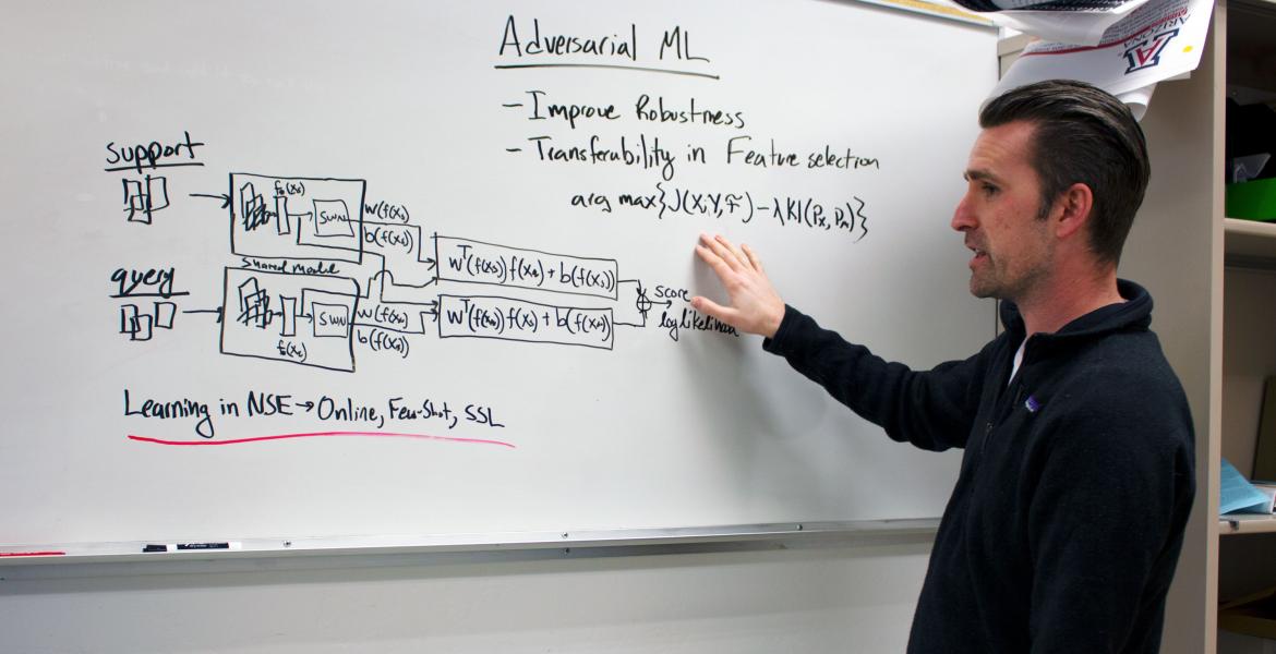 Gregory Ditzler explains a concept at a whiteboard.