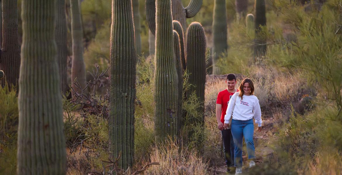 two University of Arizona students walk through a desert landscape