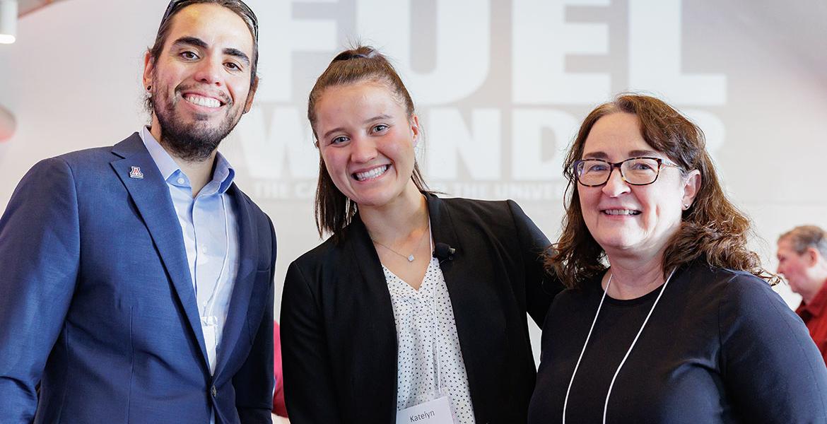 Three people pose indoors