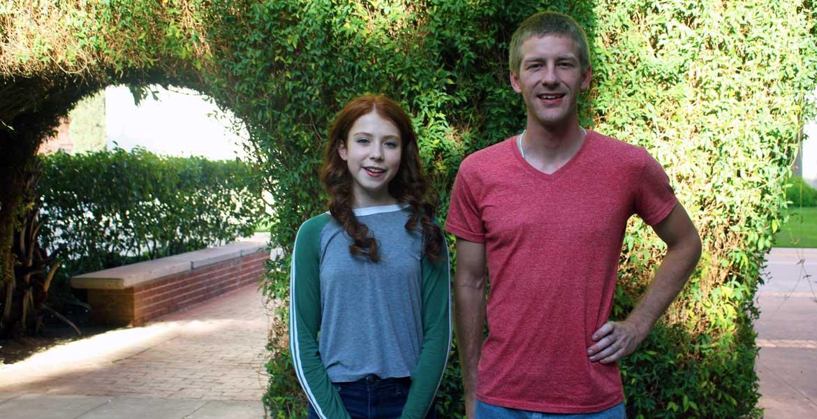 Two people standing in front of an ivy-covered archway on the UA campus.