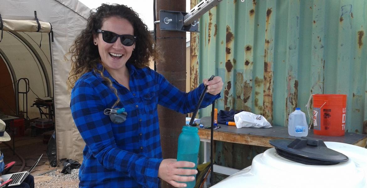 Vicky Karanikola smiling, wearing sunglasses and holding a water bottle.