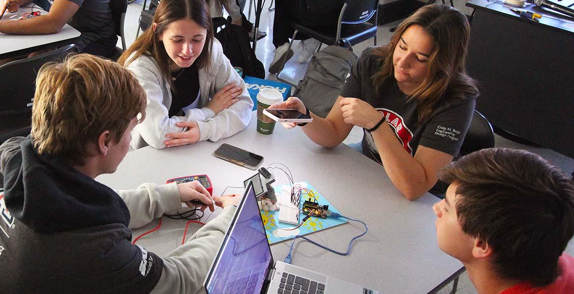 Four students test a small solar device in a classroom
