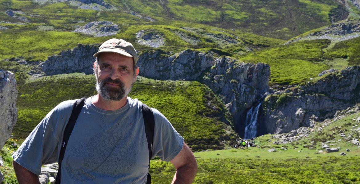 Jim Field on a hike smiling with a green landscape behind him