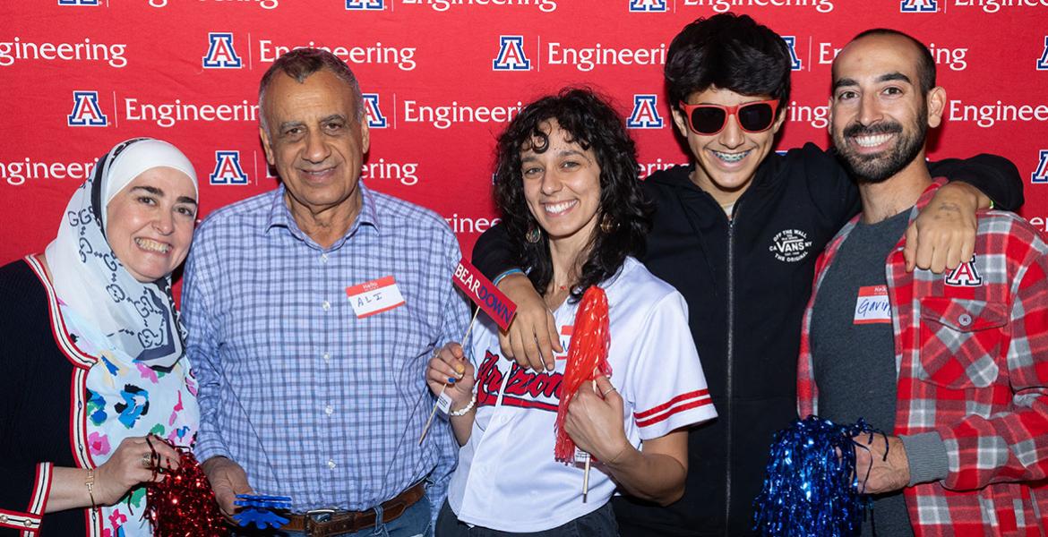 Five people pose in front of a photo background