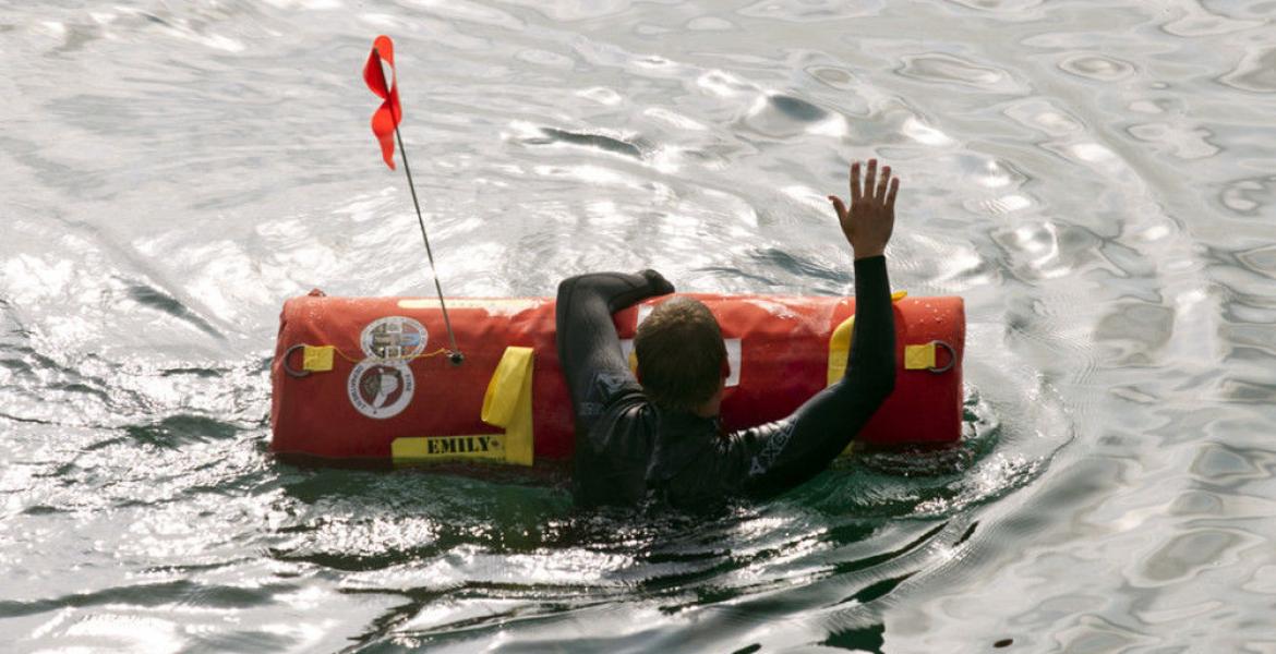 A swimmer in a wet suit holds onto an EMILY robotic rescue buoy