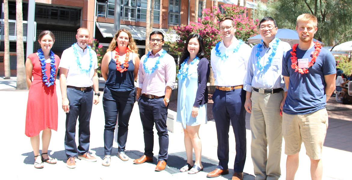 Eight faculty members smiling and wearing red and blue leis.