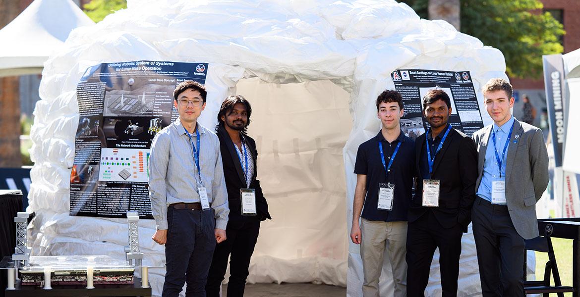 Students stand in front of the tall sandbag structure outdoors