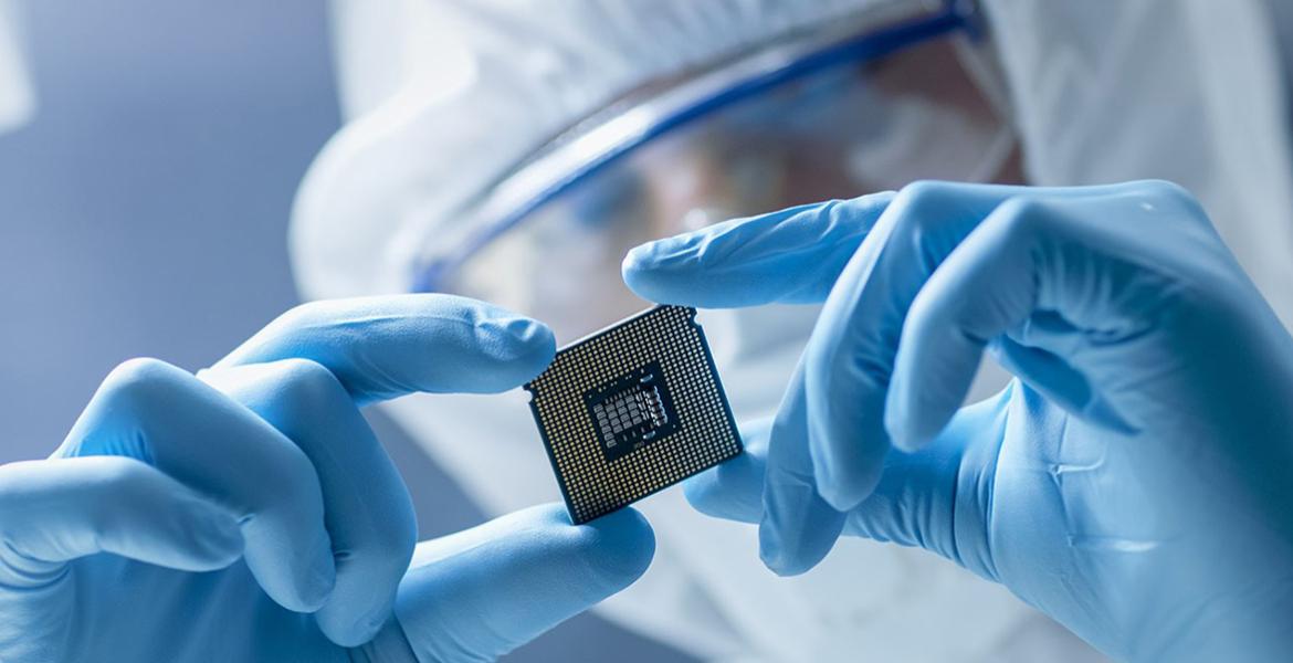 A gloved worker holds a computer chip