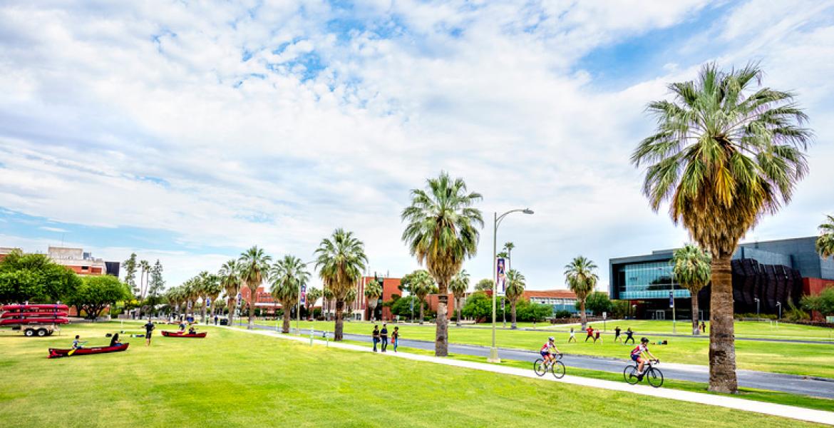 A shot of the UA Mall on a sunny day. Students are riding bikes and walking in the sunshine.