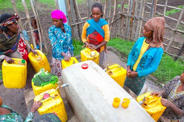 Mari Tuji, with purple headscarf, and her neighbors collect water from one of 10 water-dispensing stations in Kelecho Gerbi, Ethiopia, built by Water1st and a local organization. (Photo courtesy of Water1st International)