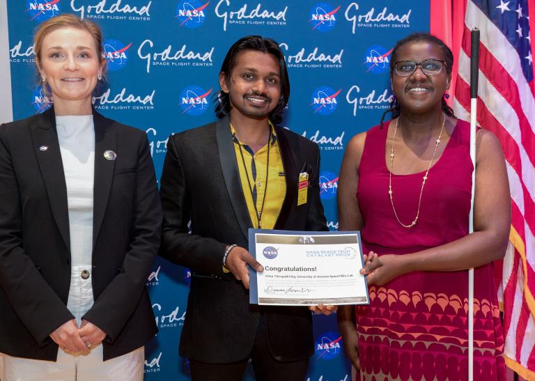 Jenn Gustetic, left, and Denna Lambert of NASA present Athip Thirupathi Raj with the Space Tech Catalyst award.