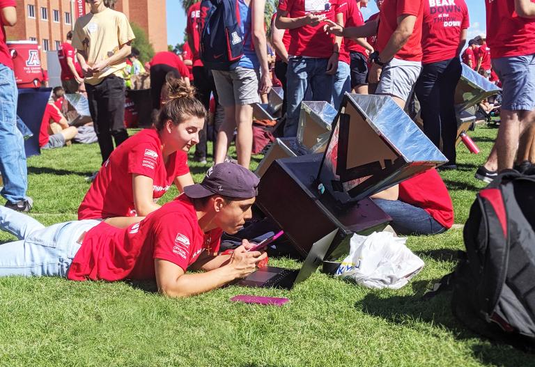 A student checks the rising temperature of his team's solar oven.