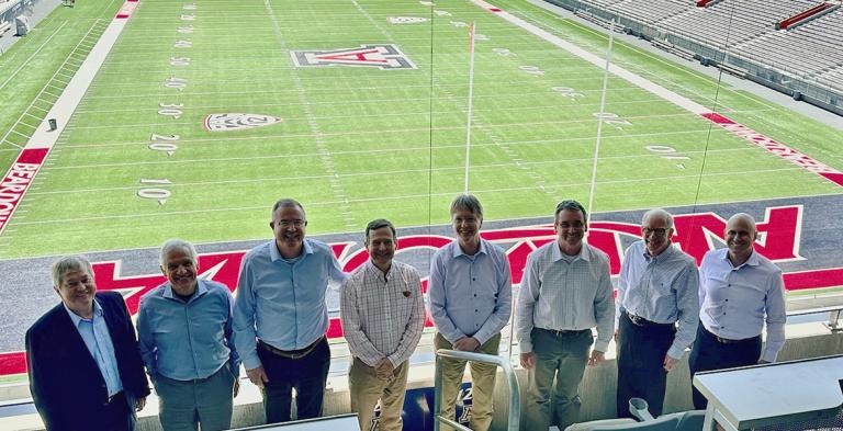 Eight engineering deans from Pac-12 universities stand in the UA football stadium with the football field behind them