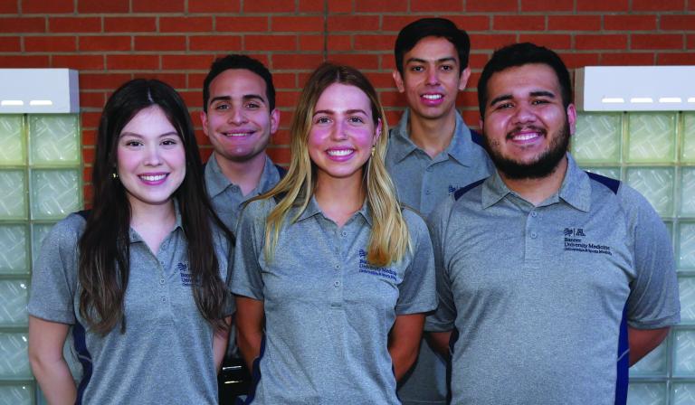 five students pose outdoors