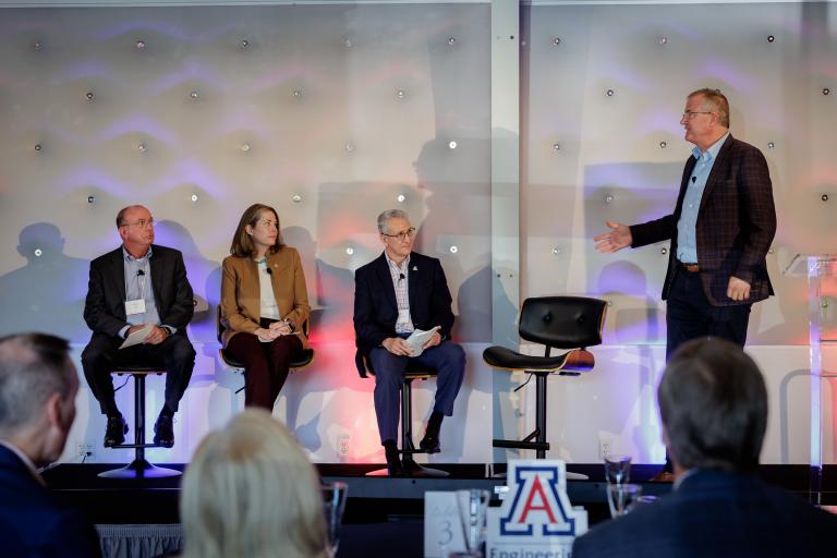 A row of panelists sits on a stage