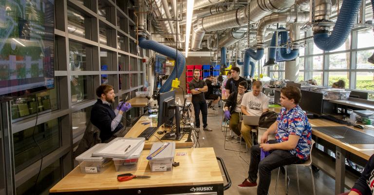 Philipp Gutruf lectures a group of students in the Peter and Nancy Salter Medical Device Lab, a space with lab equipment and a wall of windows letting in lots of natural light.