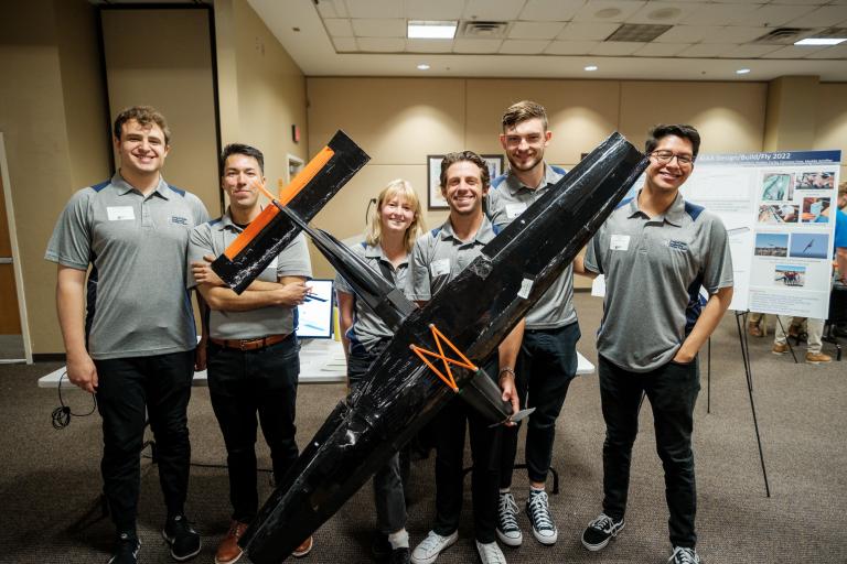 six people stand holding an airplane, with an approximately 6-foot wingspan