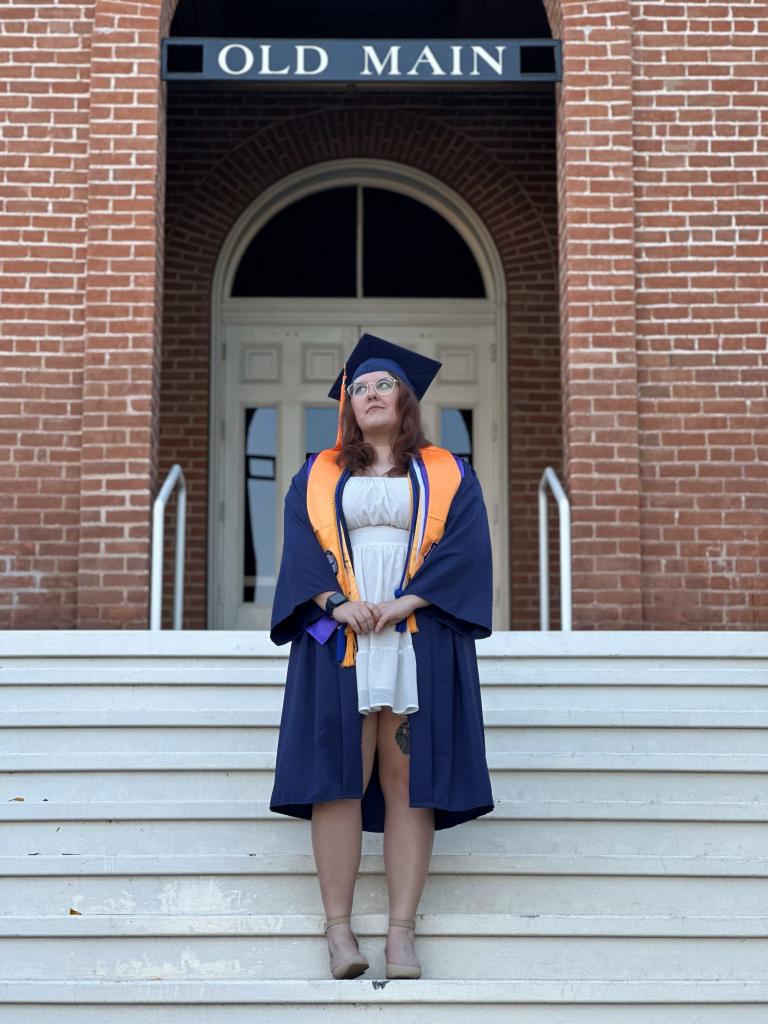 Avery Stockdale-Stephens in graduation garb on the steps of Old Main on the University of Arizona campus