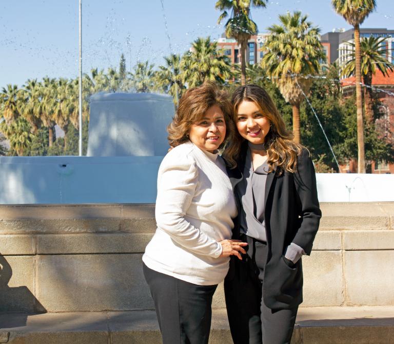 Jocelyne Rivera and her mother standing in front of a fountain.