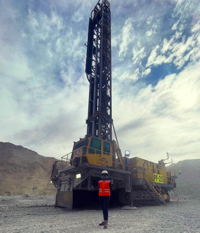 Nathalie Risso stands outdoors in front of a large mining transport vehicle