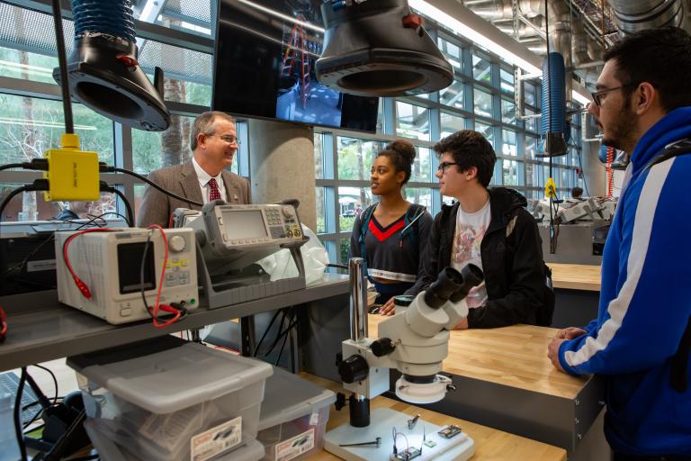 A group of students stand in the Salter Lab speaking with Dean David W. Hahn