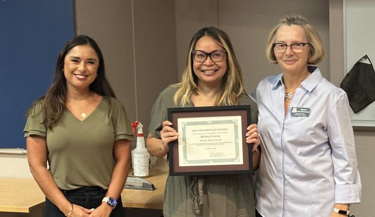 three people pose with an award certificate