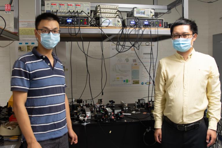 Quntao Zhuang and Zheshen Zhang, standing in a lab and wearing masks.