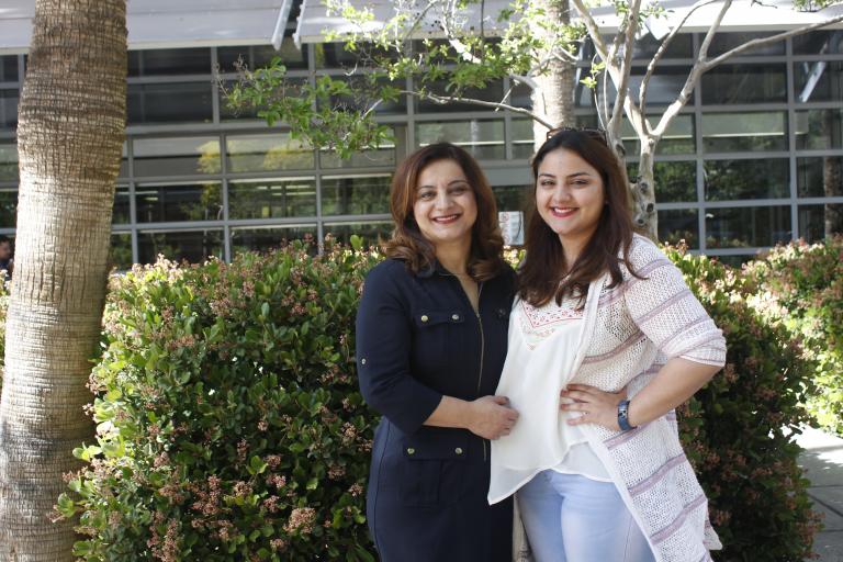 Two women stand in the shade in a UA courtyard.