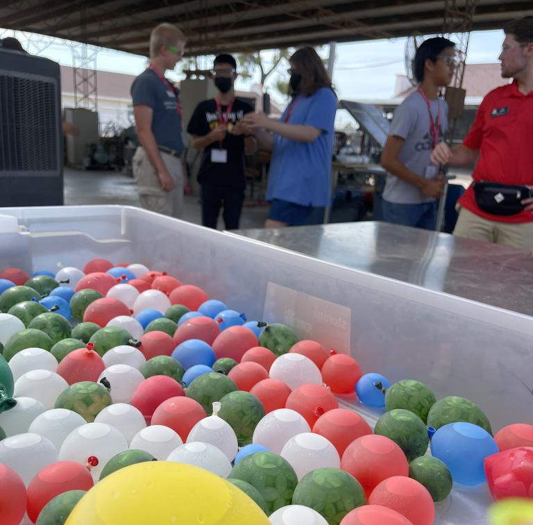 a container full of water balloons with students behind it