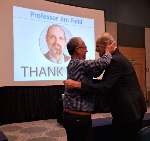 Lema and Field in front of a screen at a symposium