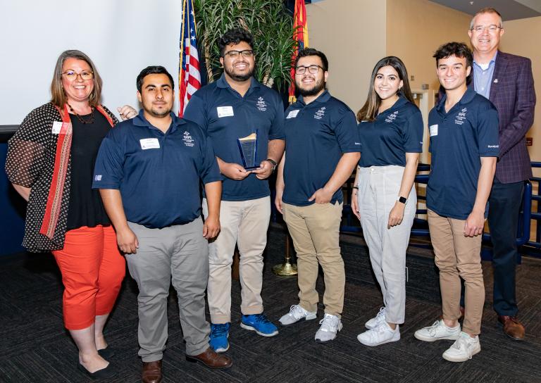 six student award recipients stand with two presenters