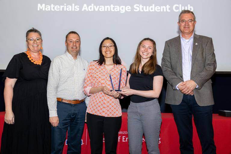 Five people pose with an award statue