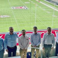 Eight engineering deans from Pac-12 universities stand in the UA football stadium with the football field behind them