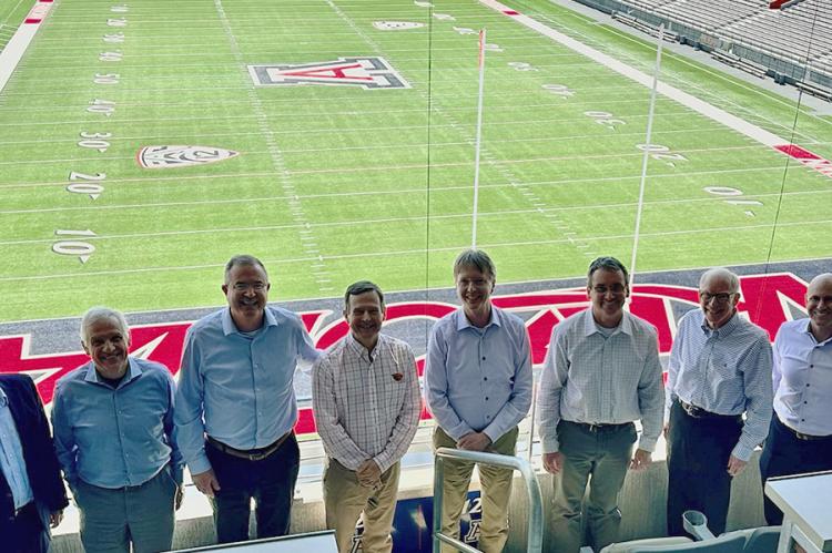 Eight engineering deans from Pac-12 universities stand in the UA football stadium with the football field behind them