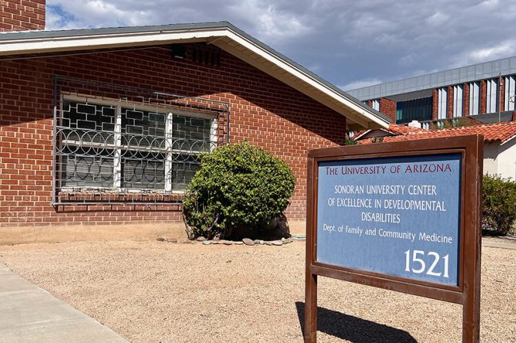 A red brick building is pictured with a blue sign in the front.