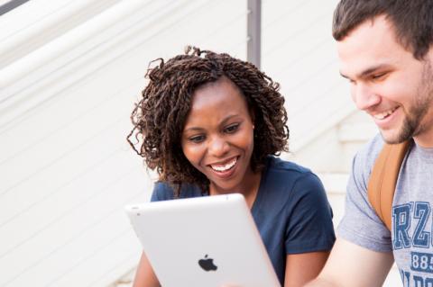 two students look at a laptop