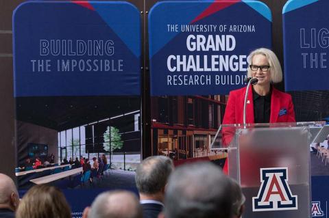 Betsy Cantwell stands at a podium in front of a crowd