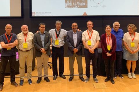 Nine people, most of whom are wearing conference lanyards, pose for a photo.